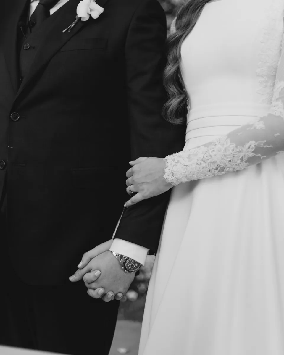 Detalhe em preto e branco das mãos e trajes do casal