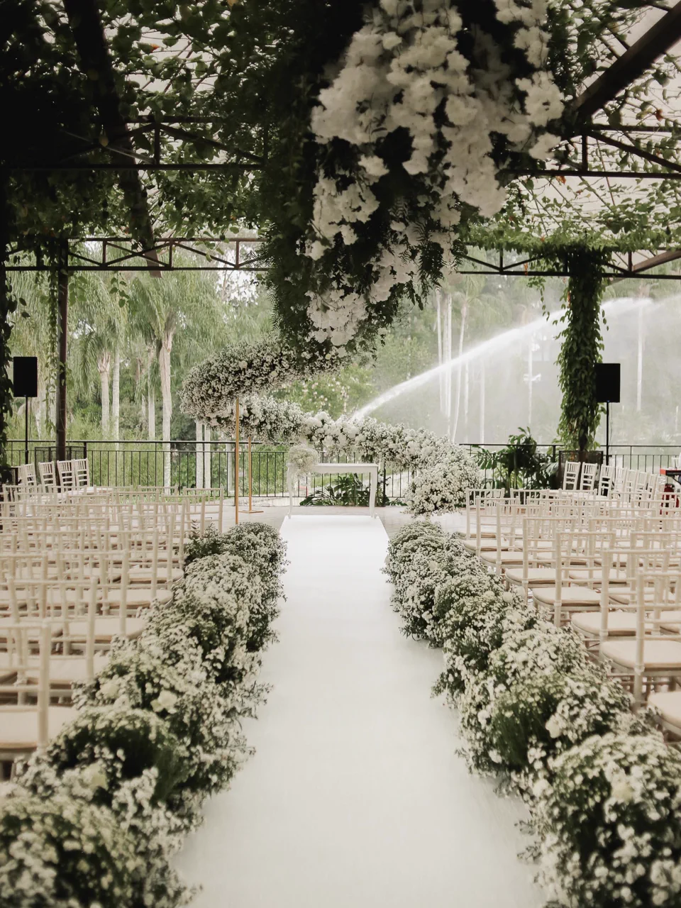 Corredor florido conduzindo ao altar, com jardim e fontes ao fundo