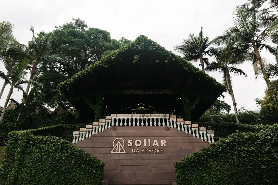 Entrada do Sollar da Árvore com o letreiro da marca, escadaria e vegetação ao redor