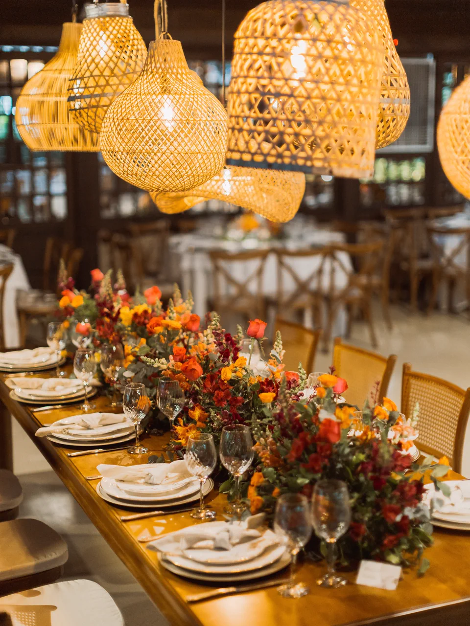 Mesa posta com flores coloridas sob luminárias de fibra no salão